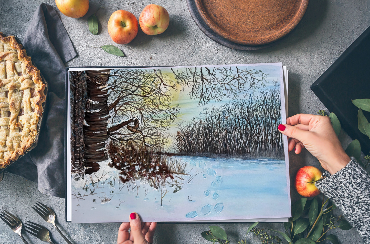 Footprints in fresh snow beside a forest of bare trees under a soft sky