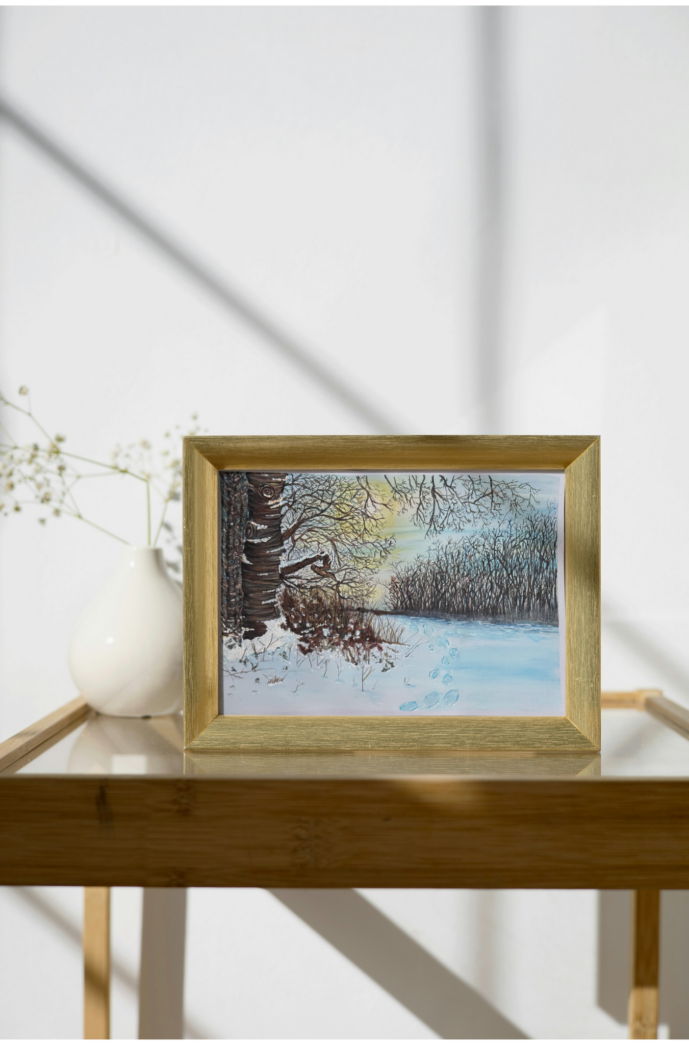 Snowy path with footprints leading into a winter forest at sunset