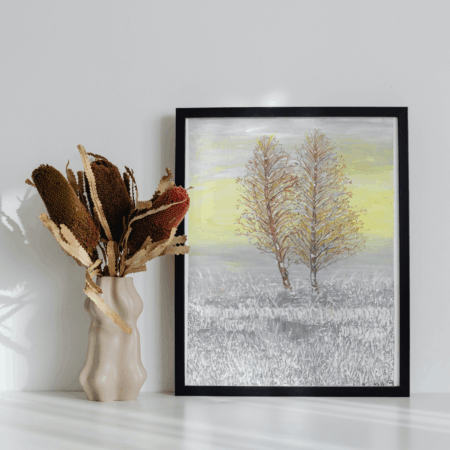 Two bare trees in a snowy field with a gray and yellow sky